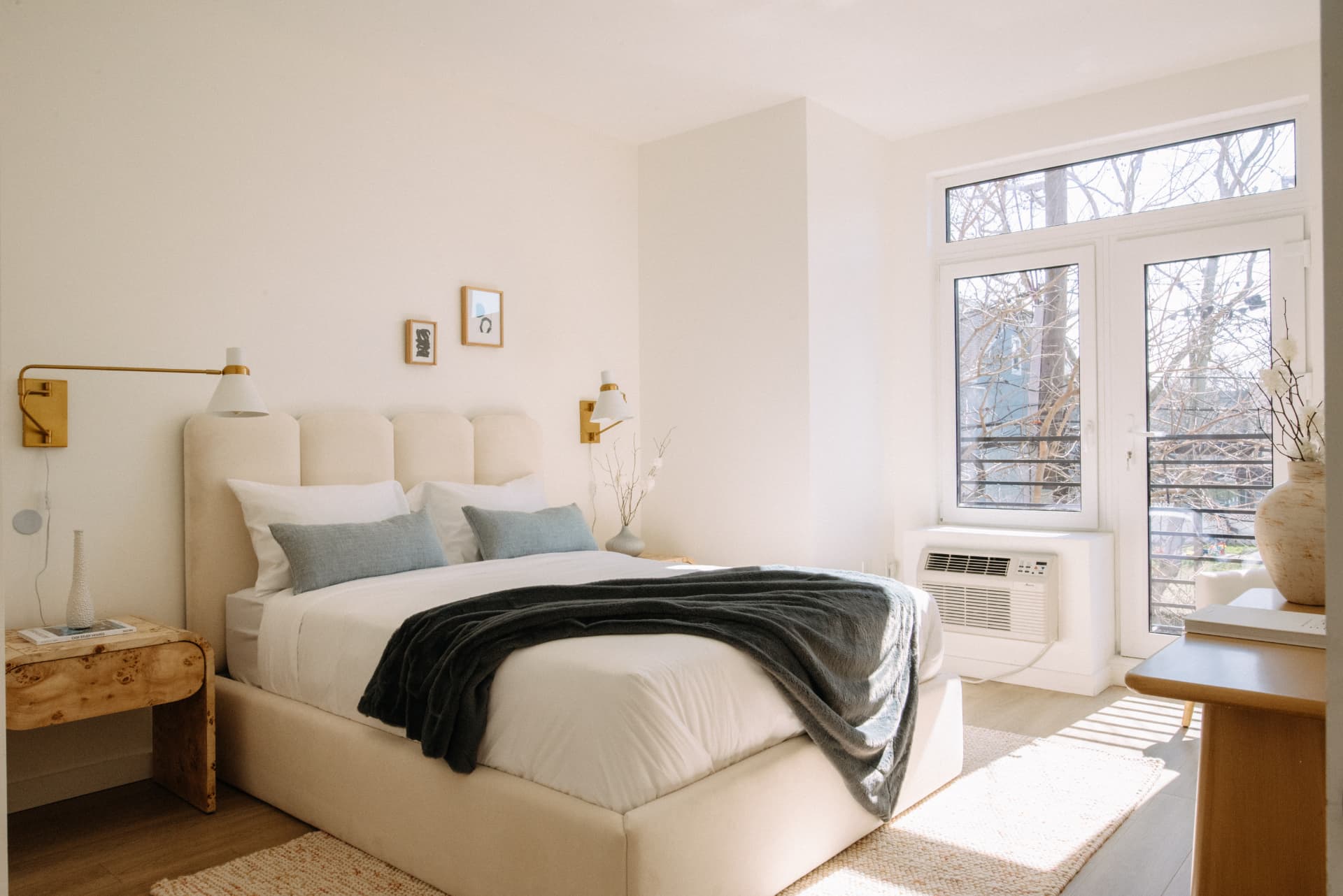 Residence bedroom with upholstered headboard, brass sconces and balcony doors