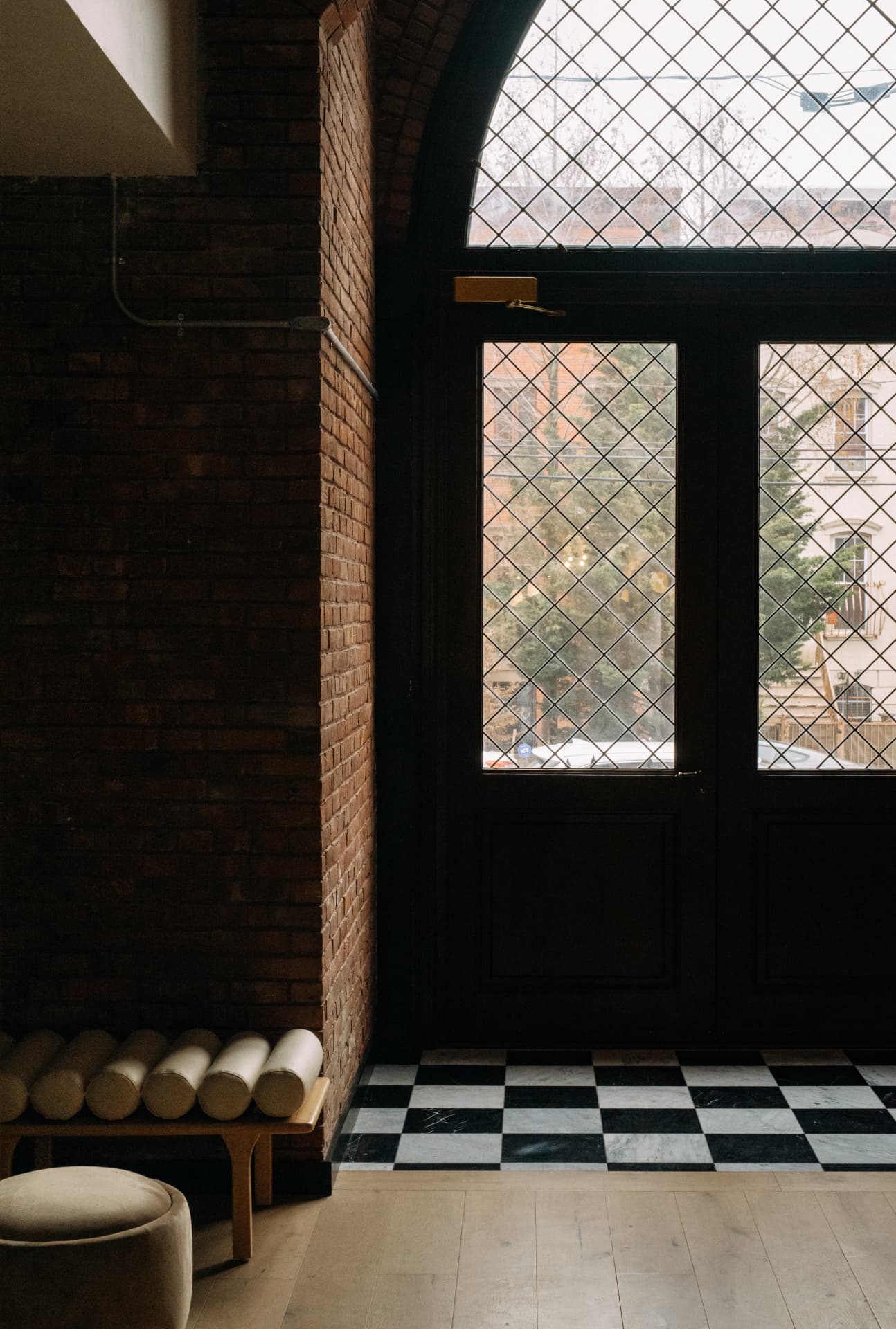 Entry vestibule with leaded glass doors, exposed brick and checkerboard marble